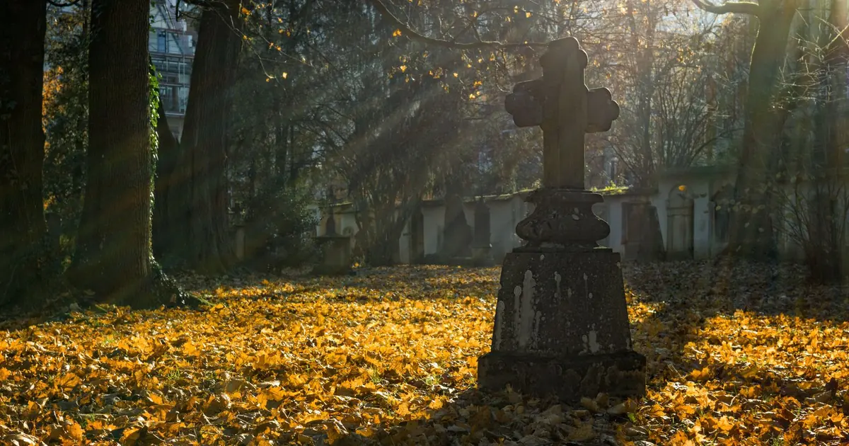 A stone grave cross in a cemetery in autumn sunlight — funeral monuments in Romania: types and prices 2026